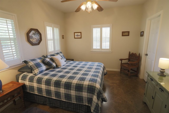 bedroom featuring baseboards, a ceiling fan, dark tile patterned floors, and multiple windows