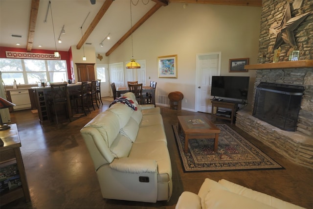 living area with visible vents, a stone fireplace, beam ceiling, and high vaulted ceiling