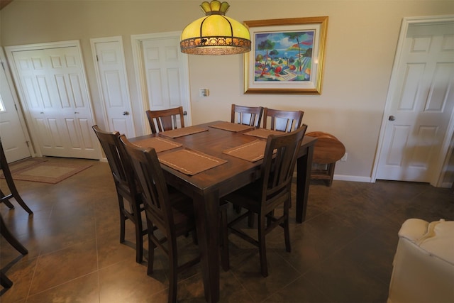 dining space with baseboards and dark tile patterned flooring
