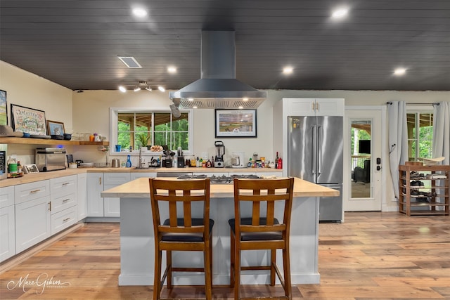 1042 N Lane Dr, Shreveport, LA 71107 - kitchen featuring white cabinets, freestanding refrigerator, extractor fan, a kitchen island, and a breakfast bar area