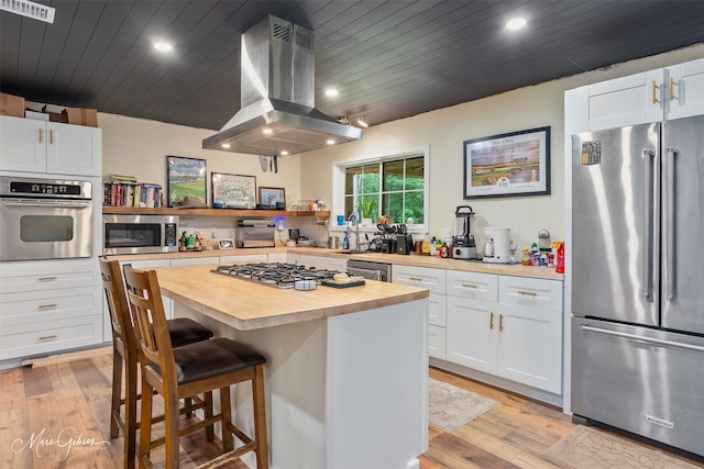 1042 N Lane Dr, Shreveport, LA 71107 - kitchen featuring island exhaust hood, visible vents, appliances with stainless steel finishes, wooden counters, and a breakfast bar area
