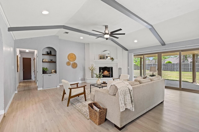 living area featuring visible vents, vaulted ceiling with beams, a brick fireplace, built in shelves, and ceiling fan