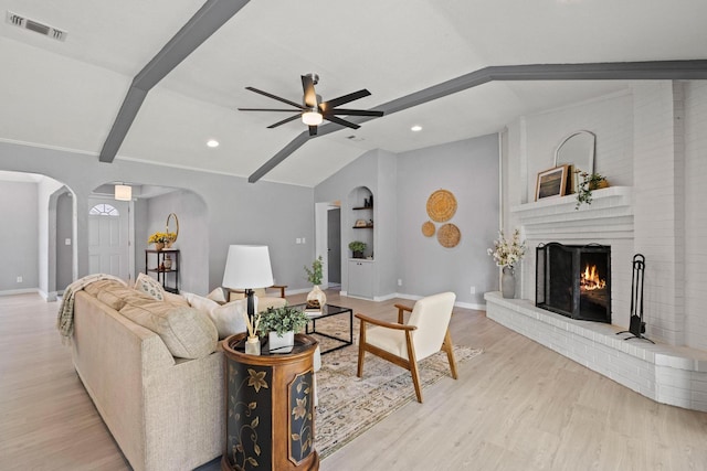 living area with lofted ceiling with beams, wood finished floors, visible vents, and arched walkways
