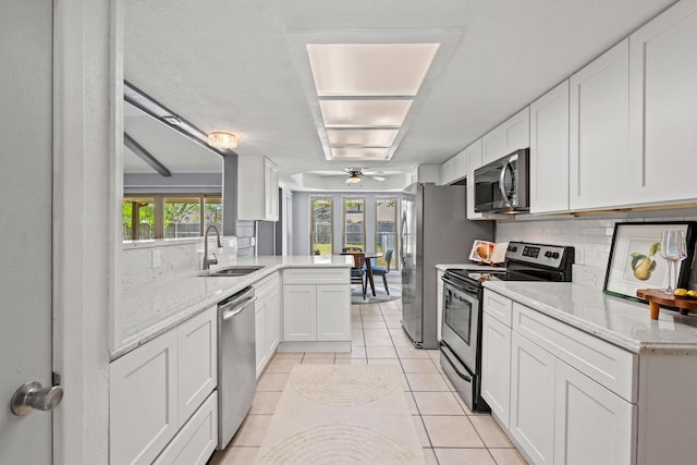 kitchen featuring a ceiling fan, a sink, tasteful backsplash, appliances with stainless steel finishes, and white cabinetry