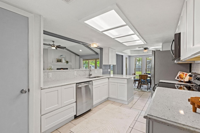 kitchen featuring a ceiling fan, a sink, a wealth of natural light, tasteful backsplash, and appliances with stainless steel finishes