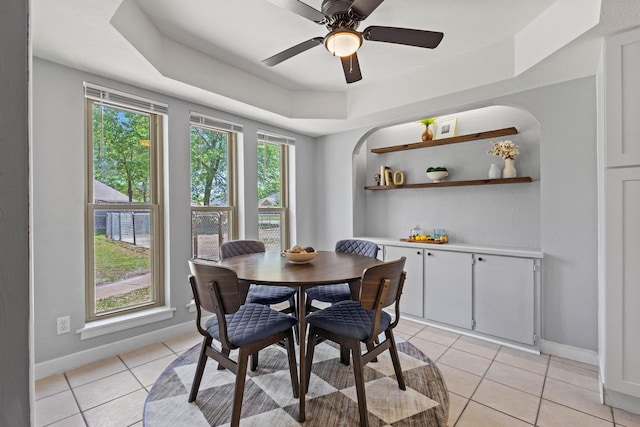 dining room featuring light tile patterned flooring, a raised ceiling, and baseboards