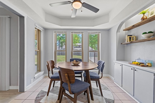 dining room with a raised ceiling, baseboards, ceiling fan, and light tile patterned floors