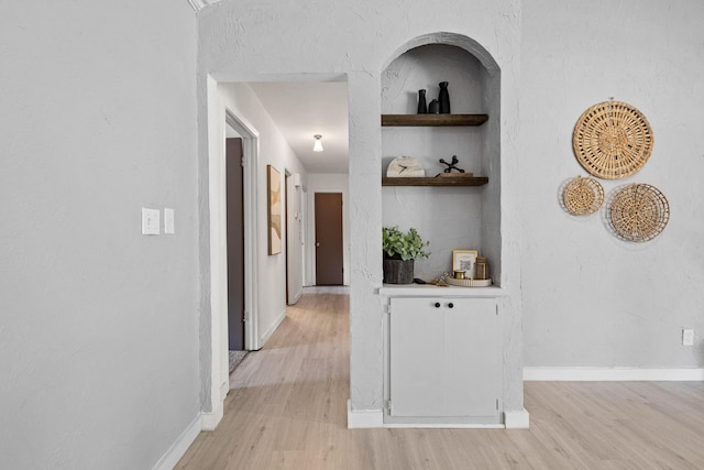 corridor with light wood-style floors and baseboards