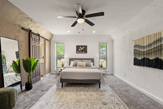 carpeted bedroom featuring a textured wall, baseboards, a textured ceiling, and a barn door