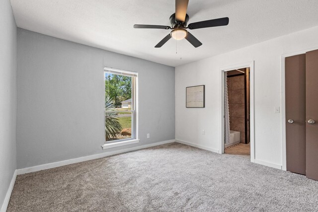 unfurnished bedroom with ceiling fan, baseboards, carpet flooring, and ensuite bathroom