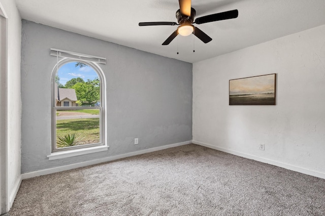 carpeted spare room featuring baseboards and a ceiling fan