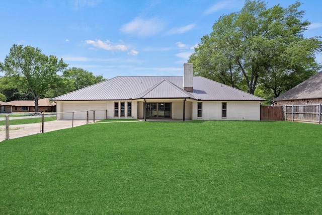 rear view of house featuring a lawn, an attached garage, driveway, and metal roof