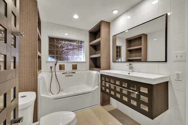 bathroom with a bath, tile walls, toilet, and vanity