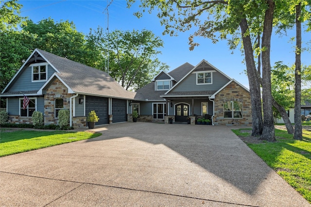 craftsman-style house with a front lawn, concrete driveway, an attached garage, covered porch, and stone siding