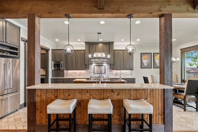 kitchen with decorative backsplash, a spacious island, a breakfast bar area, wall chimney exhaust hood, and appliances with stainless steel finishes