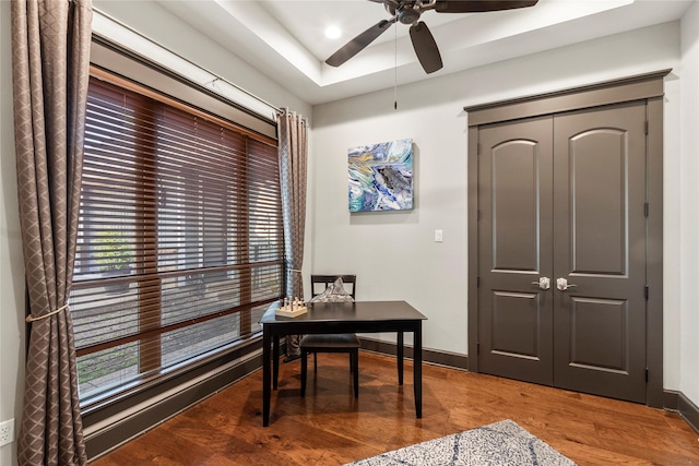 office featuring ceiling fan, baseboards, a tray ceiling, and wood finished floors