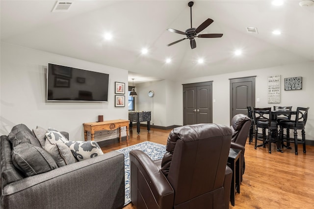 living room with light wood finished floors, vaulted ceiling, visible vents, and ceiling fan