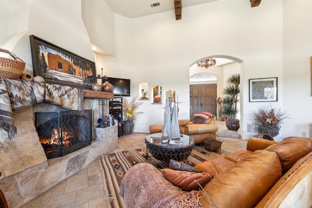 living area with beamed ceiling, arched walkways, a high ceiling, and a fireplace