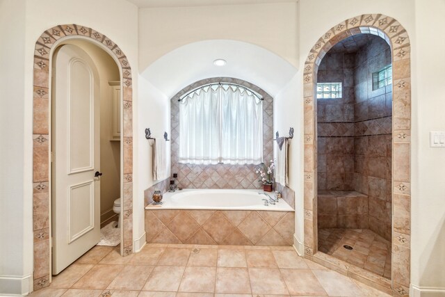 full bath featuring tile patterned floors, tiled shower, toilet, and a bath