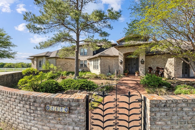 view of front facade with brick siding, a gate, and fence private yard