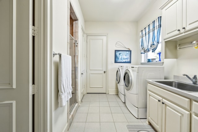 clothes washing area with a sink, light tile patterned floors, washing machine and dryer, and cabinet space