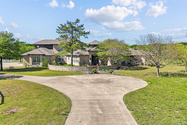 view of front of property with curved driveway and a front lawn