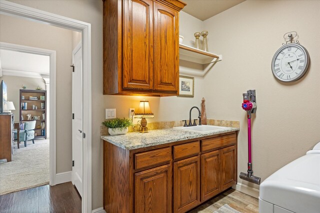 laundry room with light wood-style floors, baseboards, cabinet space, and a sink
