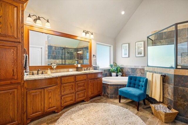 bathroom with double vanity, a garden tub, a stall shower, wood finished floors, and a sink