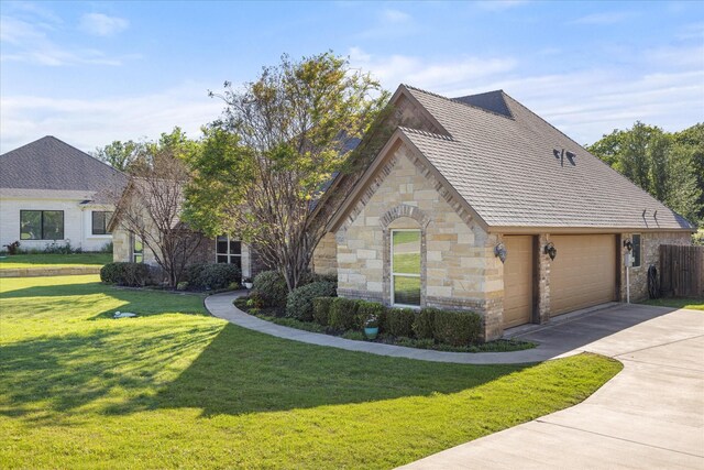 view of front of house with fence, stone siding, a garage, a front yard, and driveway