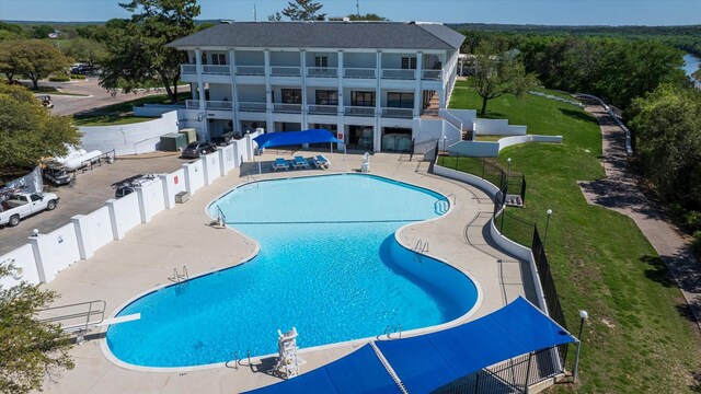 pool featuring a yard, a patio, and fence