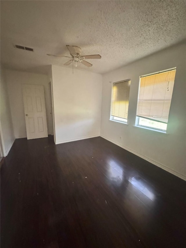 spare room with a ceiling fan, wood finished floors, a textured ceiling, baseboards, and visible vents