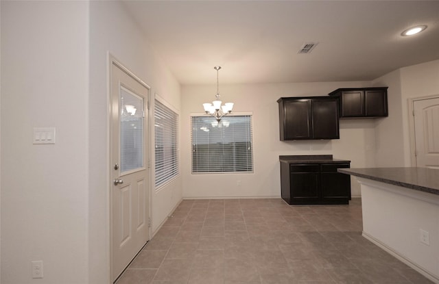 kitchen with dark countertops, light tile patterned floors, decorative light fixtures, a notable chandelier, and visible vents