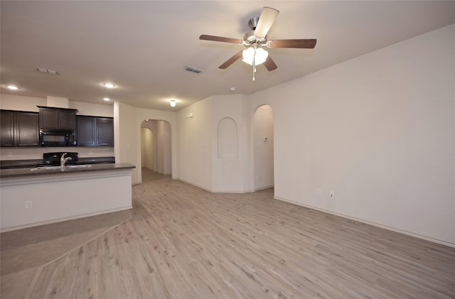 kitchen with arched walkways, a sink, dark countertops, visible vents, and black microwave
