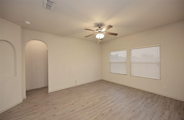 empty room with ceiling fan, arched walkways, visible vents, and light wood-style flooring
