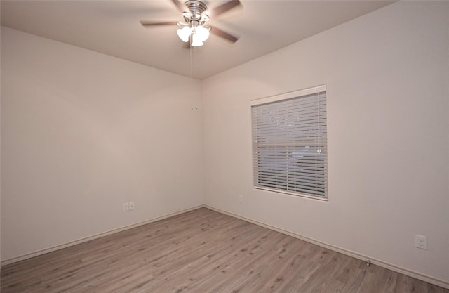 spare room featuring light wood-type flooring, a ceiling fan, and baseboards