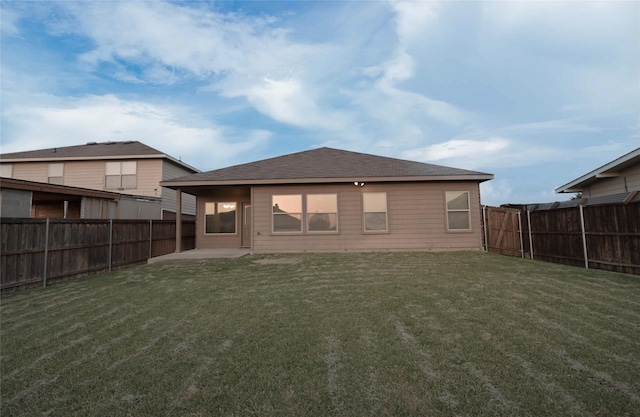 back of house with a fenced backyard, a patio area, and a lawn