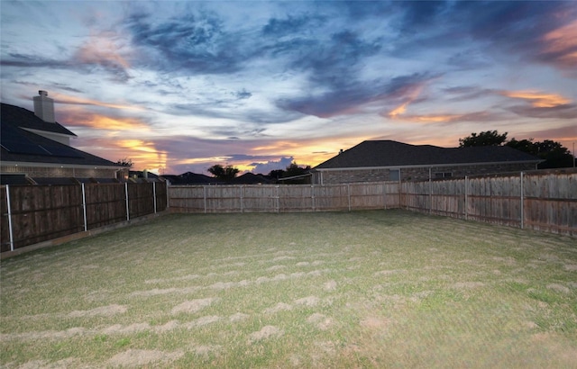 yard at dusk featuring a fenced backyard
