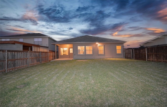 back of property with a fenced backyard and a yard