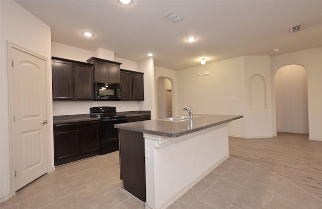 kitchen featuring black appliances, arched walkways, dark countertops, and a sink