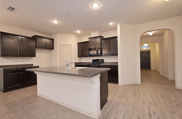 kitchen with arched walkways, a sink, dark countertops, visible vents, and black appliances
