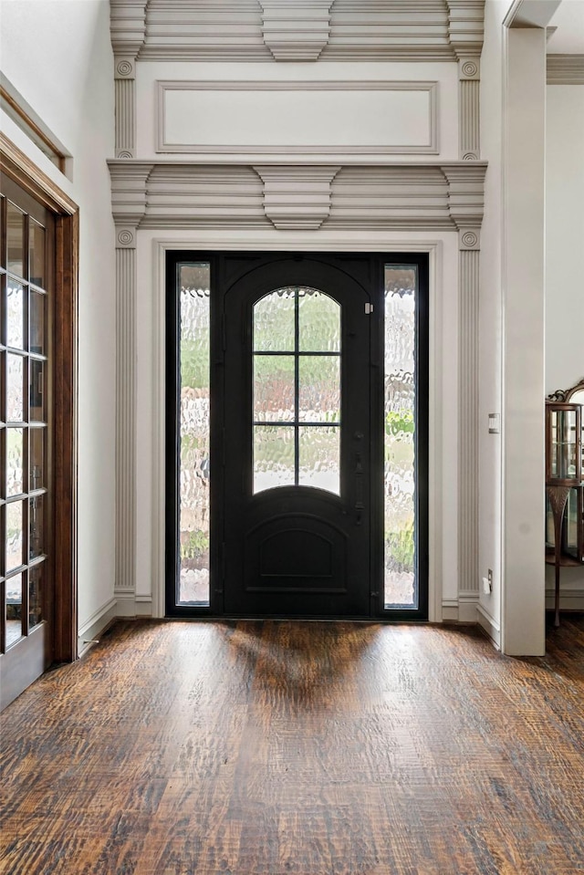 foyer featuring wood finished floors, baseboards, and ornamental molding