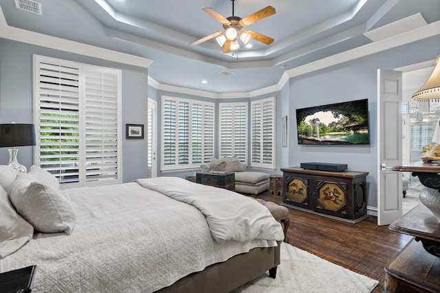 bedroom with multiple windows, wood finished floors, visible vents, and a tray ceiling