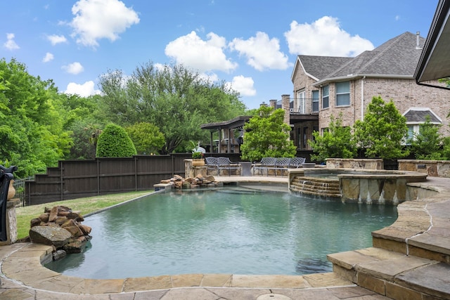 view of swimming pool with a pool with connected hot tub and fence