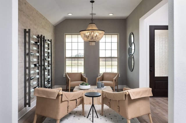 sitting room featuring wood finished floors, an inviting chandelier, and lofted ceiling