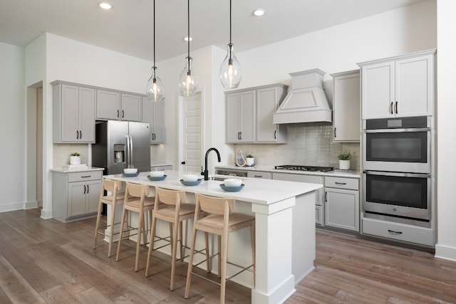 kitchen with gray cabinets, custom exhaust hood, and appliances with stainless steel finishes