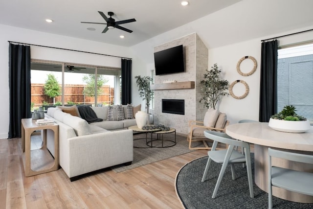 living room featuring light wood finished floors, a ceiling fan, recessed lighting, and a fireplace