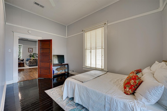 bedroom with crown molding, multiple windows, visible vents, and hardwood / wood-style floors