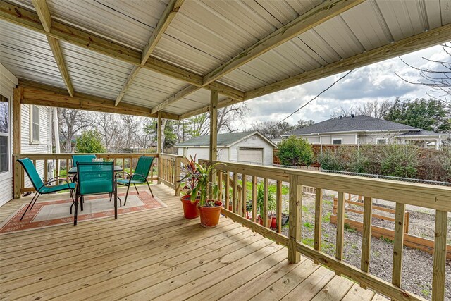 wooden deck with fence, a detached garage, an outdoor structure, and outdoor dining space