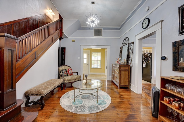 foyer entrance with visible vents, baseboards, a notable chandelier, wood finished floors, and stairs