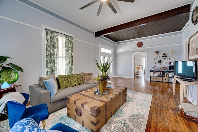 living area with beamed ceiling, a ceiling fan, and wood-type flooring